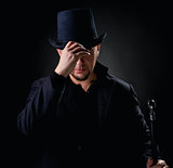 Handsome man wearing black hat and jacket holding stick