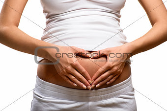 Woman holding her hands in a heart shape on her pregnant belly 