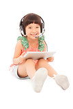 little student girl sitting and holding a tablet with earphone.