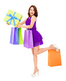 smiling young woman holding shopping bag and a gift box