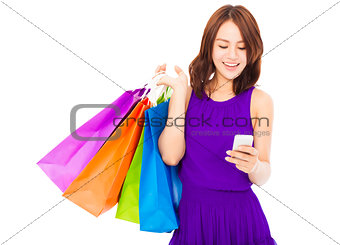 happy young woman holding shopping bags and mobile phone 
