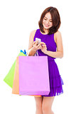happy young woman holding shopping bags and mobile phone