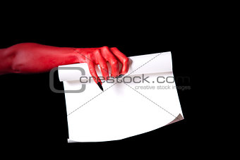 Red devil hand holding paper scroll 