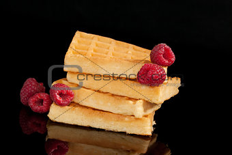 Delicious waffles with raspberries isolated on black.