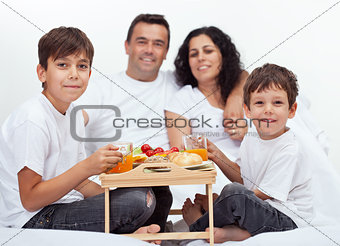 Family with two boys having breakfast in bed