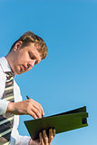 Businessman signs documents on sky background