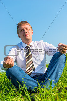 happy businessman relaxes in a field in the lotus position