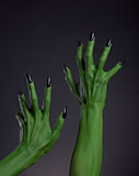 Green witch hands with black nails stretching up, real body-art 