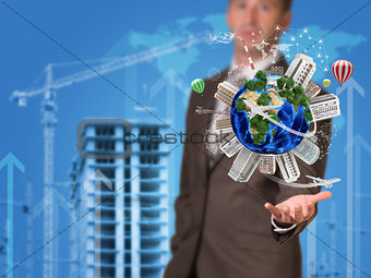Businessman holding earth. Buildings as backdrop