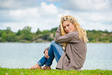 Blond woman sitting at lake
