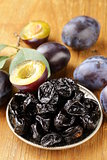 Dried plums prunes and fresh berries on the wooden table