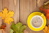 Autumn leaves and coffee cup over wood background