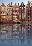 Typical Amsterdam houses reflected in the canal with blue sky background
