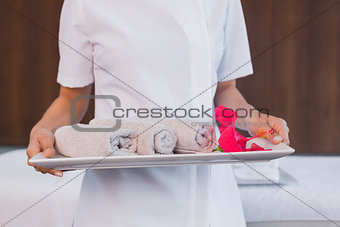 Mid section of masseur holding rolled up towels