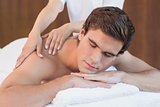 Young man receiving shoulder massage at spa center