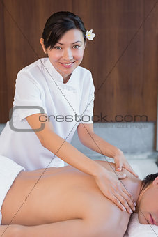 Female masseur massaging mans back at spa center