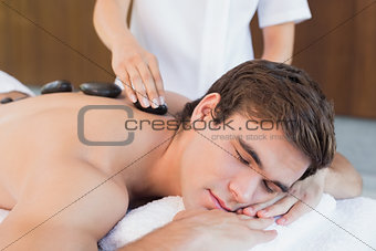 Young man receiving stone massage at spa center