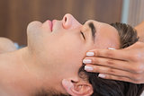 Man receiving head massage at spa center