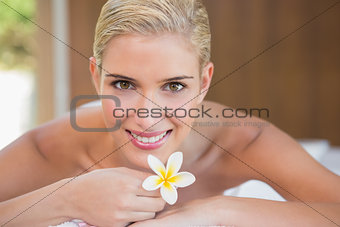 Woman holding flower on massage table at spa center