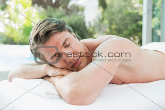 Handsome man lying on massage table at spa center