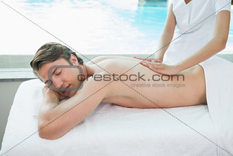 Handsome man receiving back massage at spa center