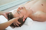 Handsome man receiving head massage at spa center