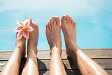 Couple feet against swimming pool on a sunny day