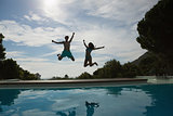 Couple jumping into swimming pool