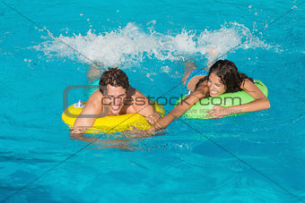 Couple in inflatable rings at swimming pool