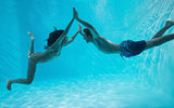 Couple holding hands and swimming underwater