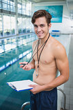 Swimming instructor holding stopwatch and clipboard by the pool