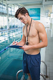 Swimming instructor writing on clipboard by the pool