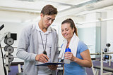 Personal trainer and client looking at clipboard together