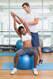 Personal trainer working with client on exercise ball