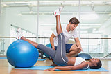 Personal trainer working with client using exercise ball