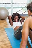 Personal trainer working with client on exercise mat