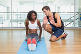 Personal trainer working with client on exercise mat