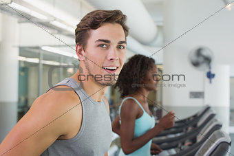 Fit man smiling at camera on treadmill