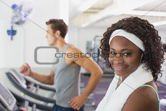 Fit woman smiling at camera on treadmill