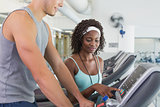 Fit woman on treadmill talking to personal trainer