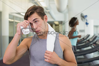 Handsome man wiping his forehead beside treadmills