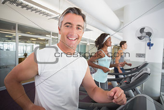 Fit man running on treadmill smiling at camera