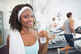Fit woman smiling at camera beside treadmills