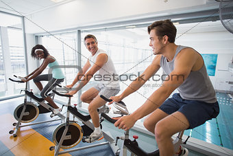 Three fit people working out on exercise bikes