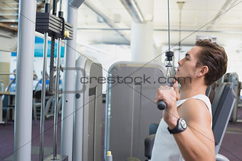 Fit man using the weights machine for his arms
