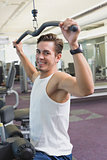 Fit man using the weights machine for his arms