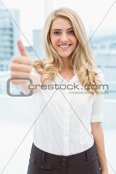 Beautiful businesswoman gesturing thumbs up in office