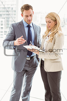 Businessman and secretary looking at diary in office
