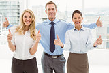 Business people gesturing thumbs up in office