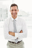 Happy businessman with arms crossed in office